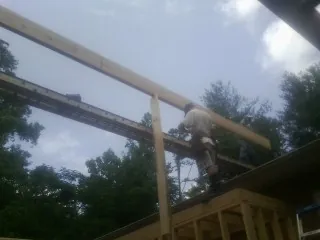 Carpenter setting a ridge beam over a new addition frame in Aripeka