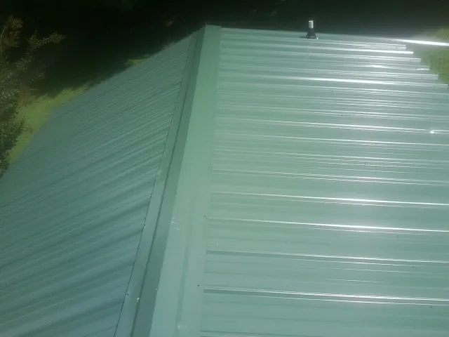 New green metal panels meeting at the ridge of a roof — Flat Roof Repair work by our crew in Aripeka