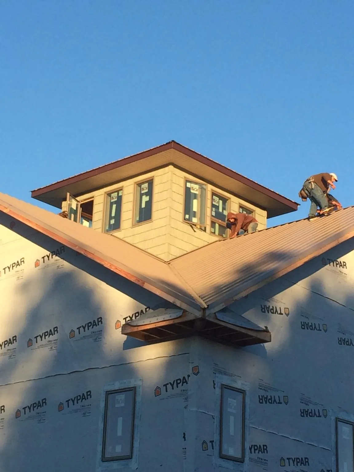 Roofers working around a rooftop cupola on a new metal roof at sunset — Roof Waterproofing in Aripeka by Roofing Brothers